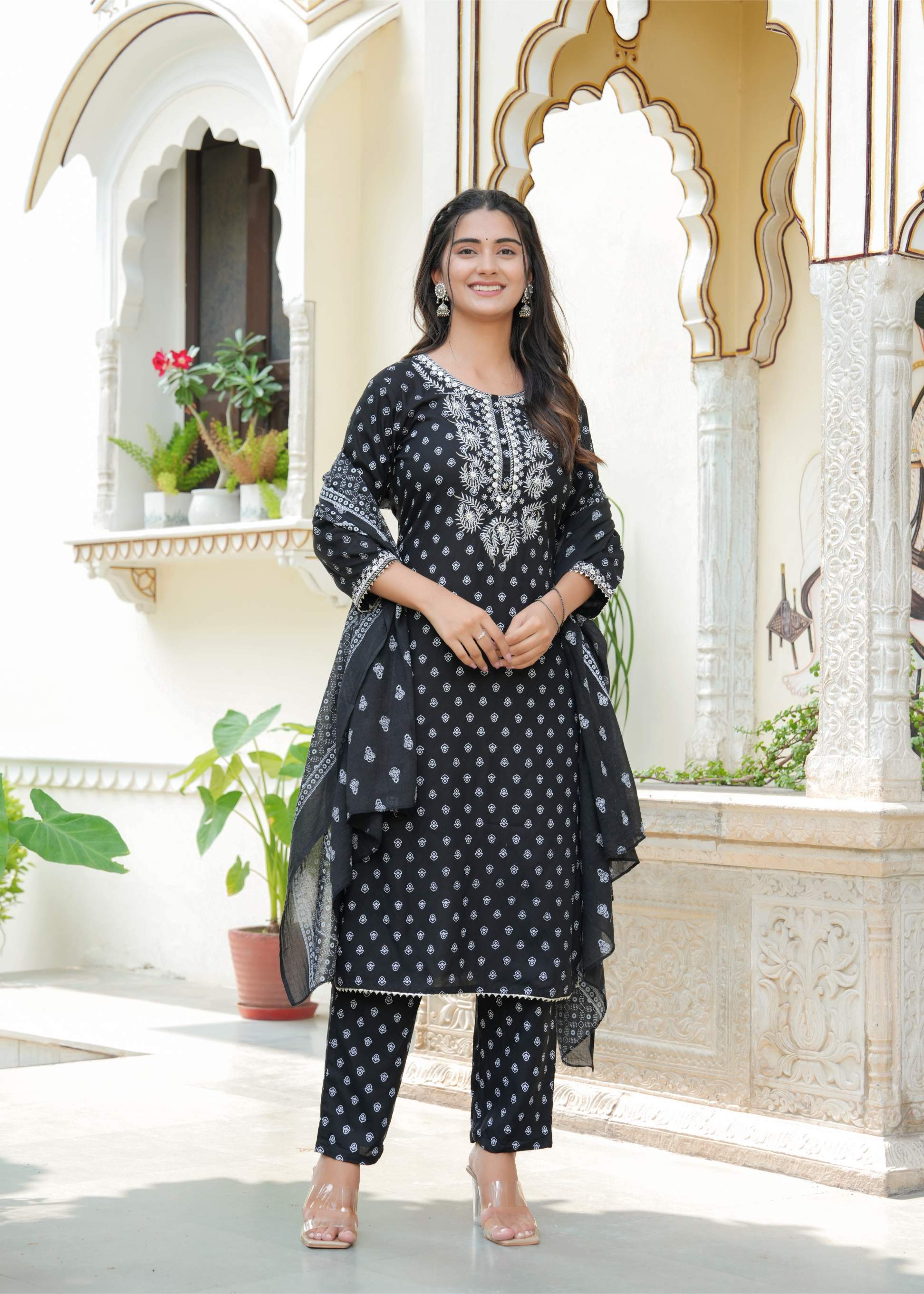 Woman in a black and white patterned outfit standing in an ornate architectural setting.